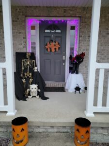 Front porch with Halloween decorations including skeletons and pumkins.